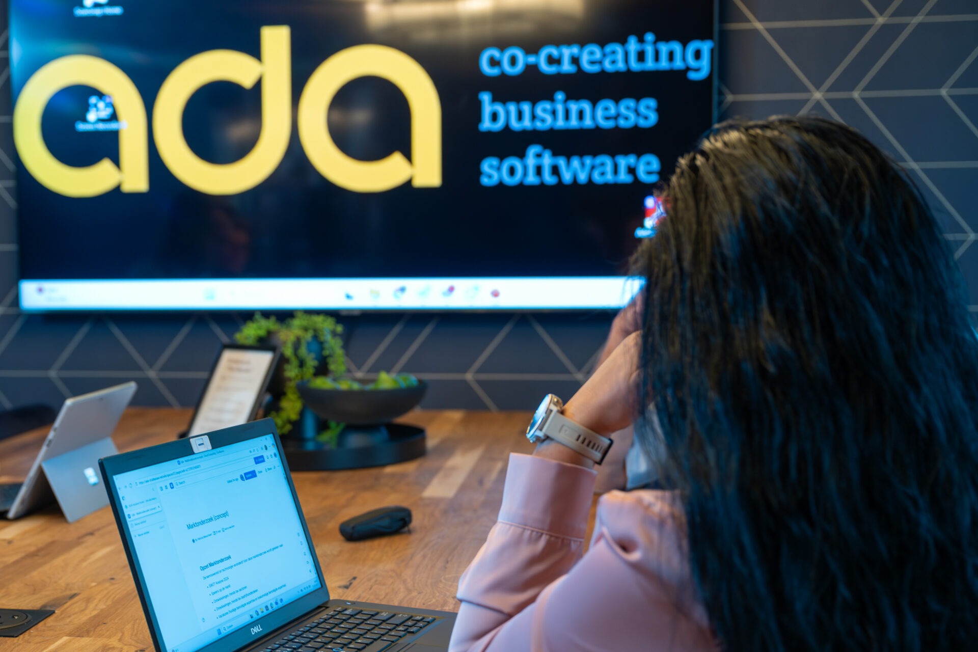 Collega werkt in een ADA vergaderruimte aan business software, met focus op samenwerking, low-code en digitale oplossingen.