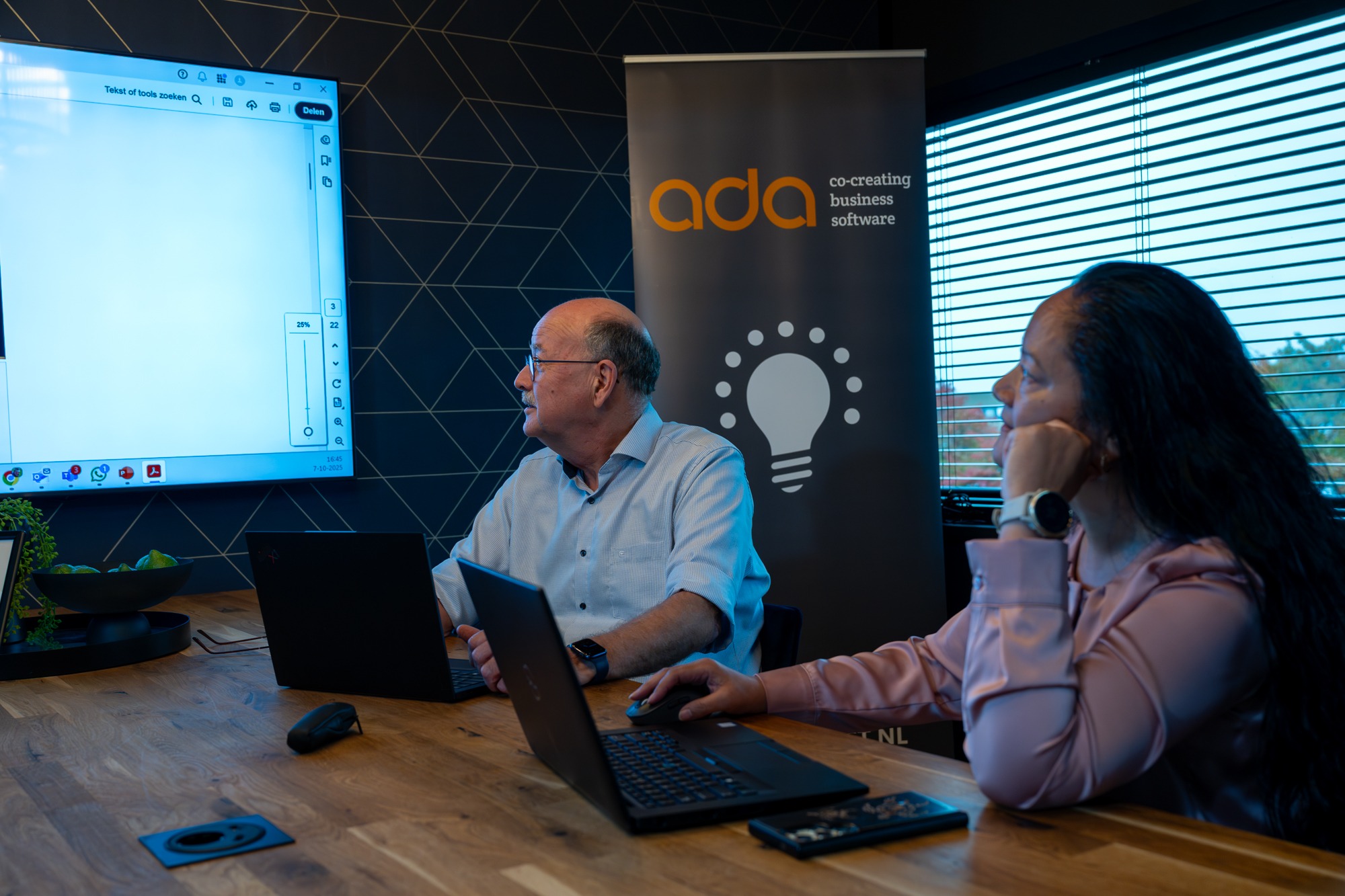 ADA specialisten werken samen aan digitale oplossingen tijdens een overleg met laptops en scherm in de vergaderruimte.