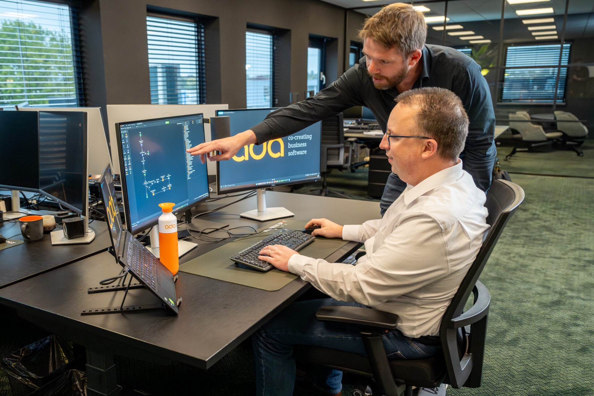Twee ADA-collega's bekijken samen de opzet van een applicatie op het scherm en wegen keuzes af die technical debt op termijn voorkomen.